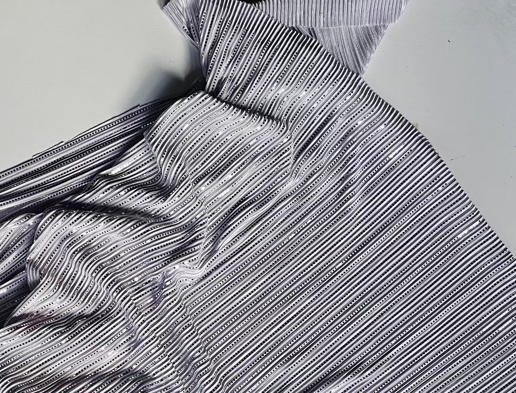 A crumpled piece of gray and white striped fabric with a subtle sheen, laid out on a light gray background.