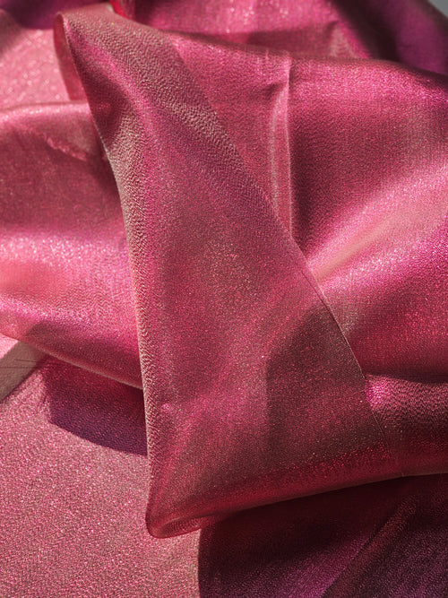 A close-up of draped pink fabric with a subtle sheen and fine texture, folded to show its lustrous surface.