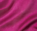 A close-up of draped magenta pink fabric with soft folds and a smooth texture.