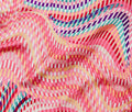 A close-up of a lightweight fabric with a vibrant, wavy striped pattern in pink, orange, yellow, teal, and purple.