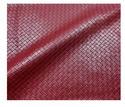 A close-up of a burgundy red textured material with a diamond-patterned embossed surface, shown with soft folds.