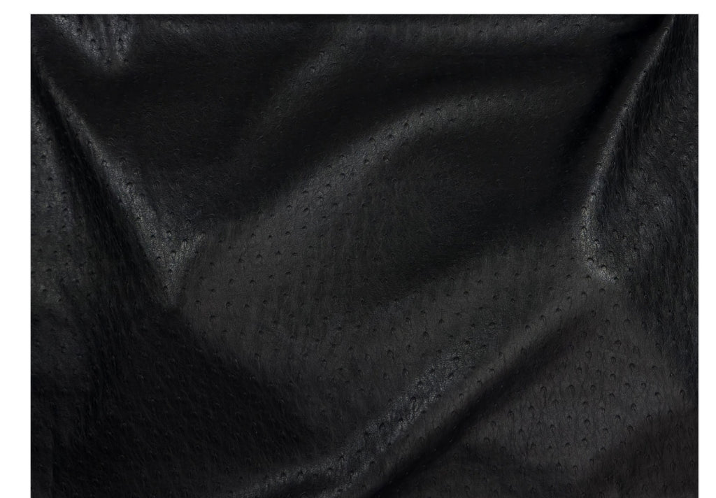 Black textured fabric with a fine dotted pattern and soft folds, shown close-up against a white border.