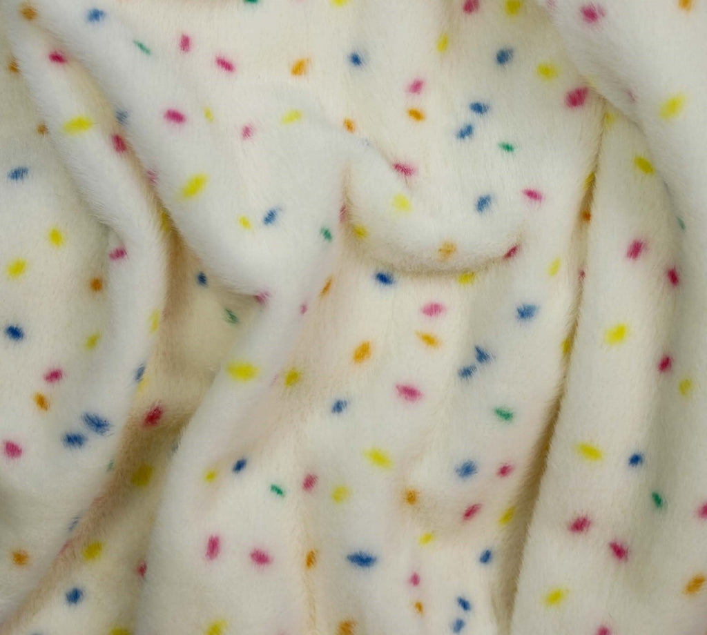 Close-up of a soft plush fabric in off-white with scattered small multicolored confetti dots in yellow, blue, pink, and orange.